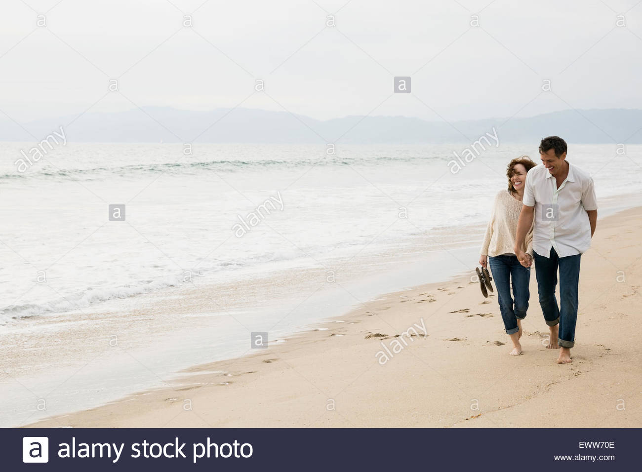 Pareja tomados de la mano y caminar en la playa Foto de stock
