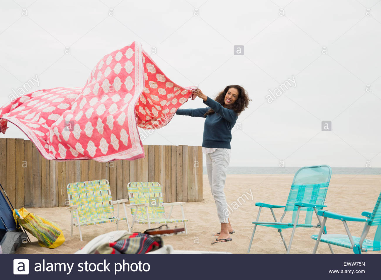 Mujer extendiendo manta para picnic en la playa Foto de stock