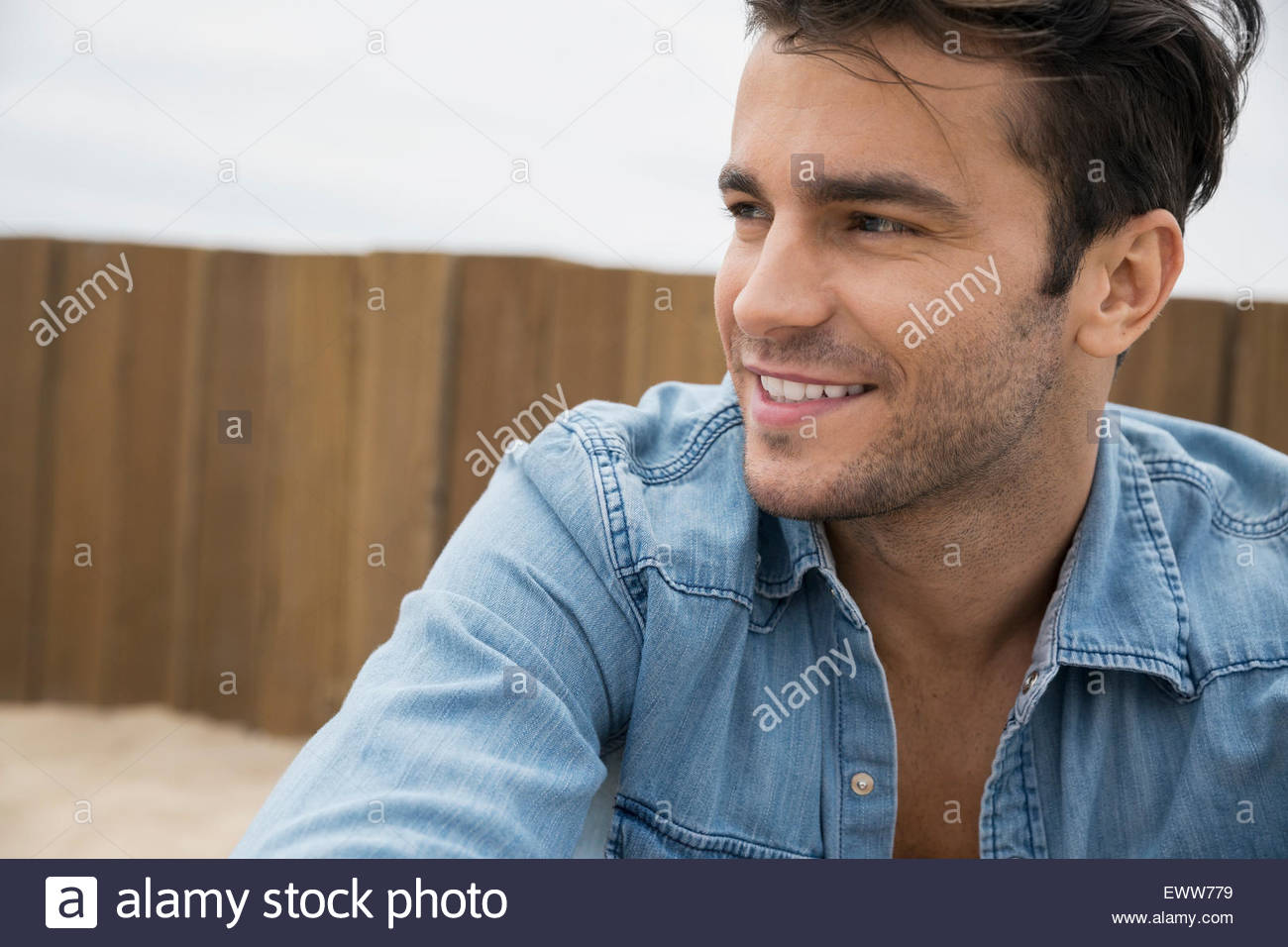 Morena sonriente al hombre con el rastrojo mirando lejos Foto de stock