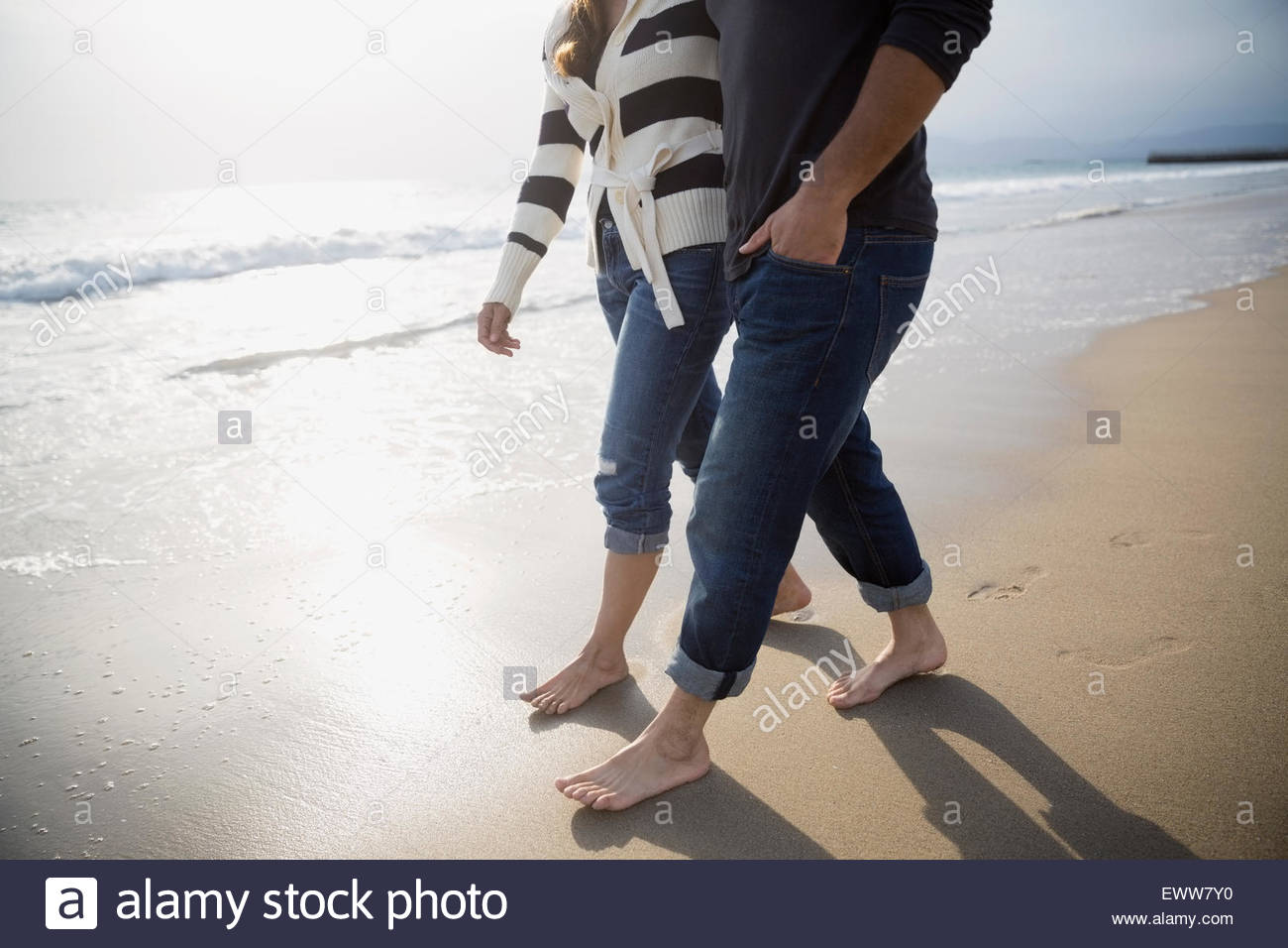 Pareja descalzos caminando en sunny beach Foto de stock