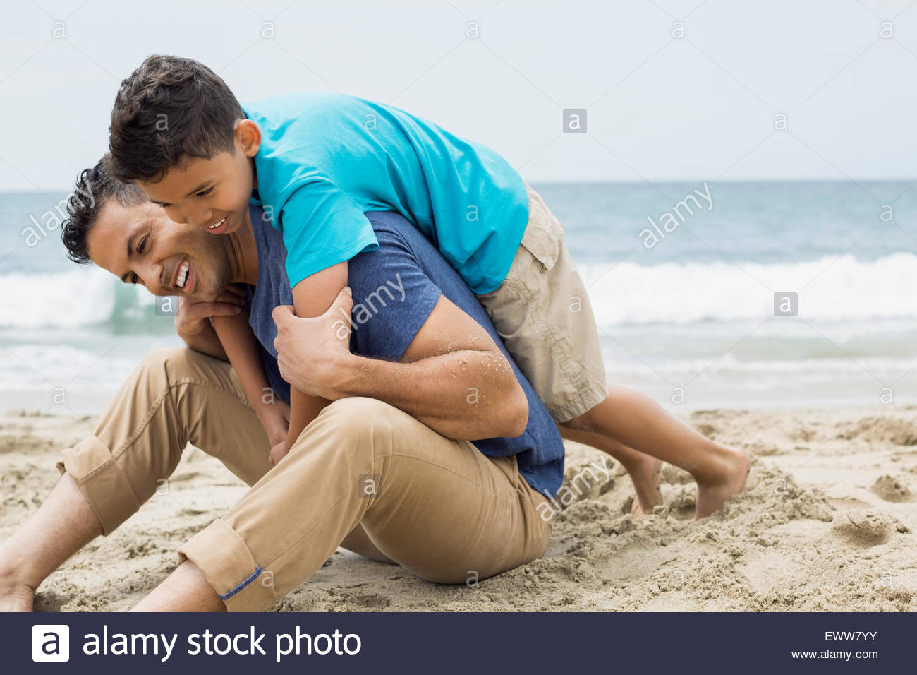 Juguetón, padre e hijo, abrazando en la playa Foto de stock