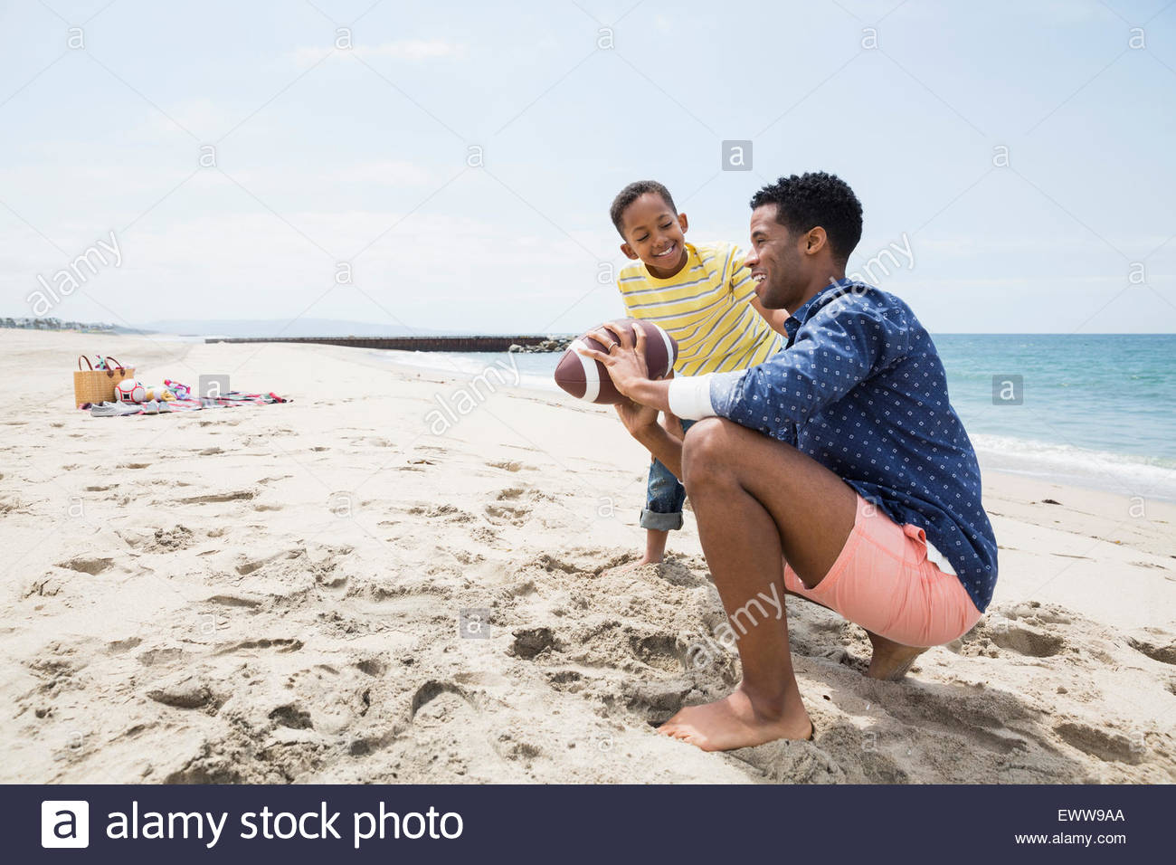 Padre hijo de enseñanza de fútbol en la playa de agarre Foto de stock