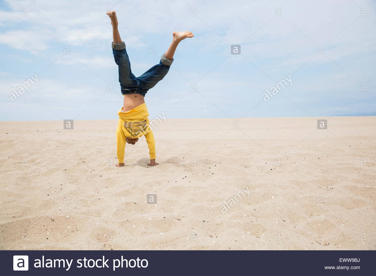 Boy haciendo pino en la playa Foto de stock
