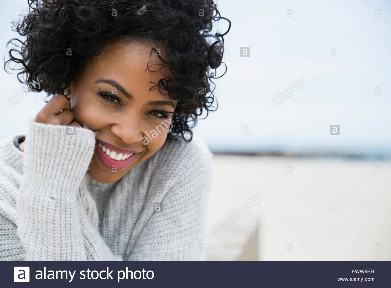 Retrato mujer sonriente rizado cabello negro en la playa Foto de stock