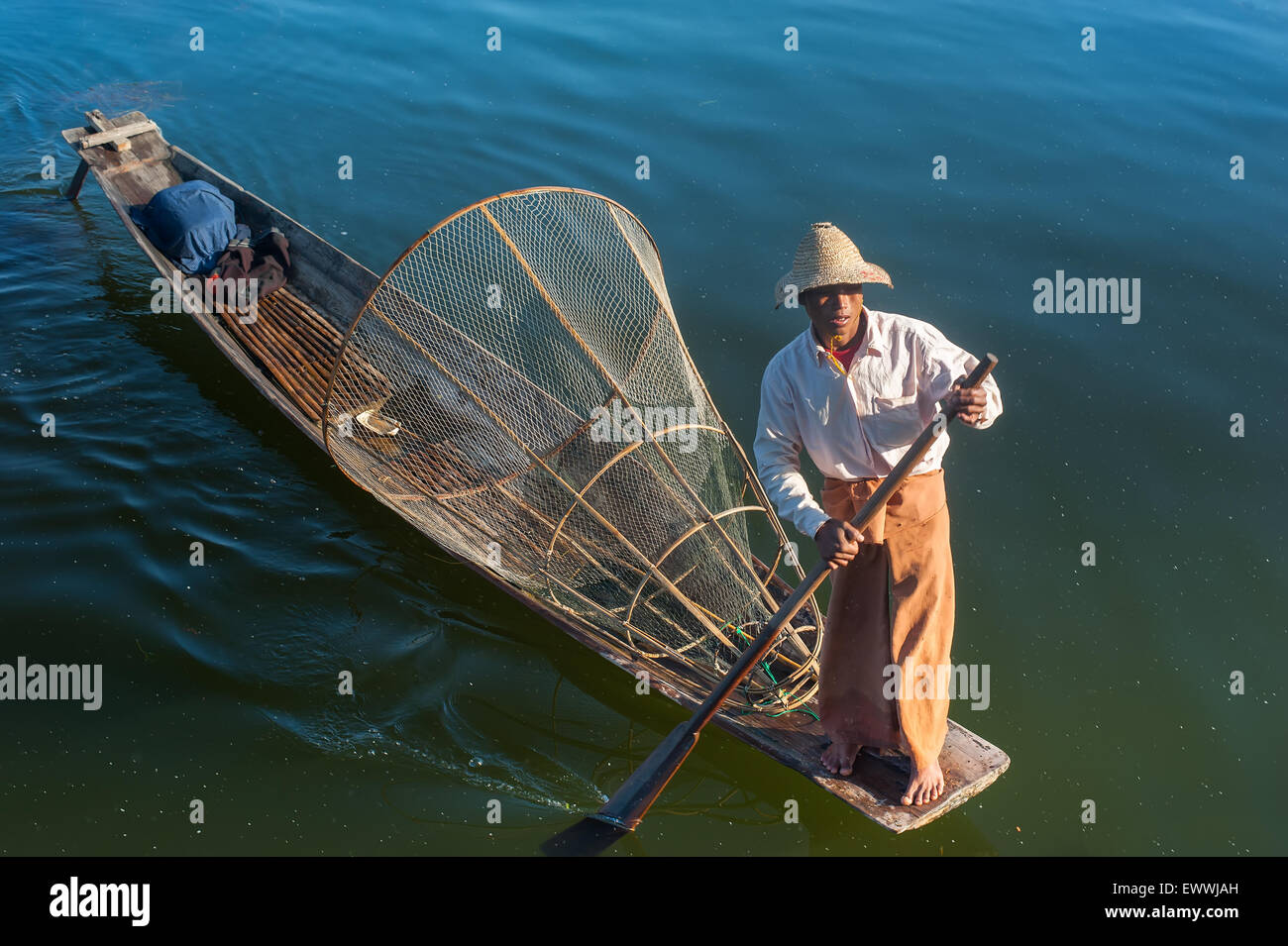 Pescador birmano en barco de bambú a la captura de peces en forma tradicional con net artesanal. Lago Inle, Myanmar (Birmania) viajes destinat Foto de stock