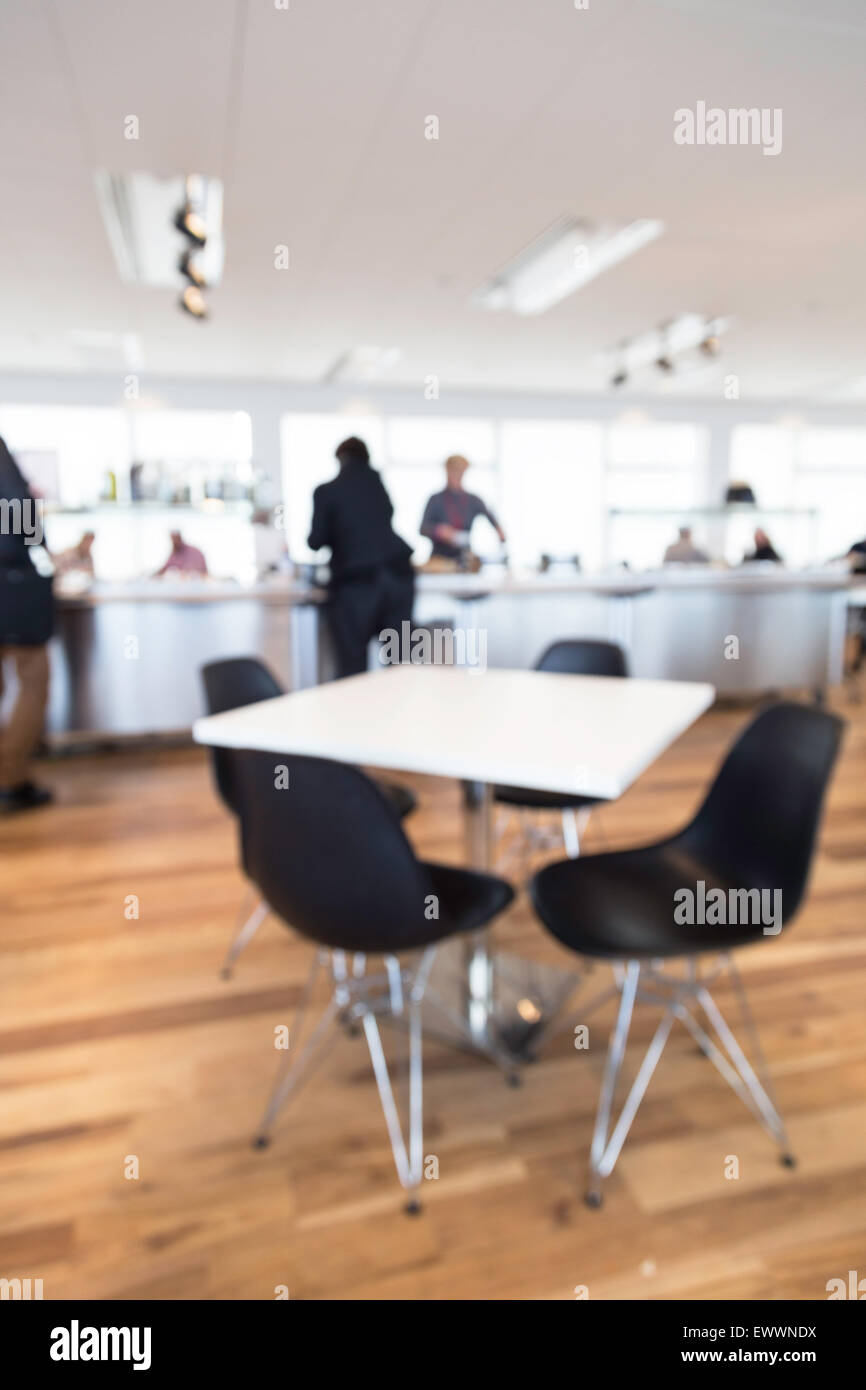Fuera de foco shot de una oficina cafetería, personas sirviendo en el mostrador con la mesa en primer plano Foto de stock