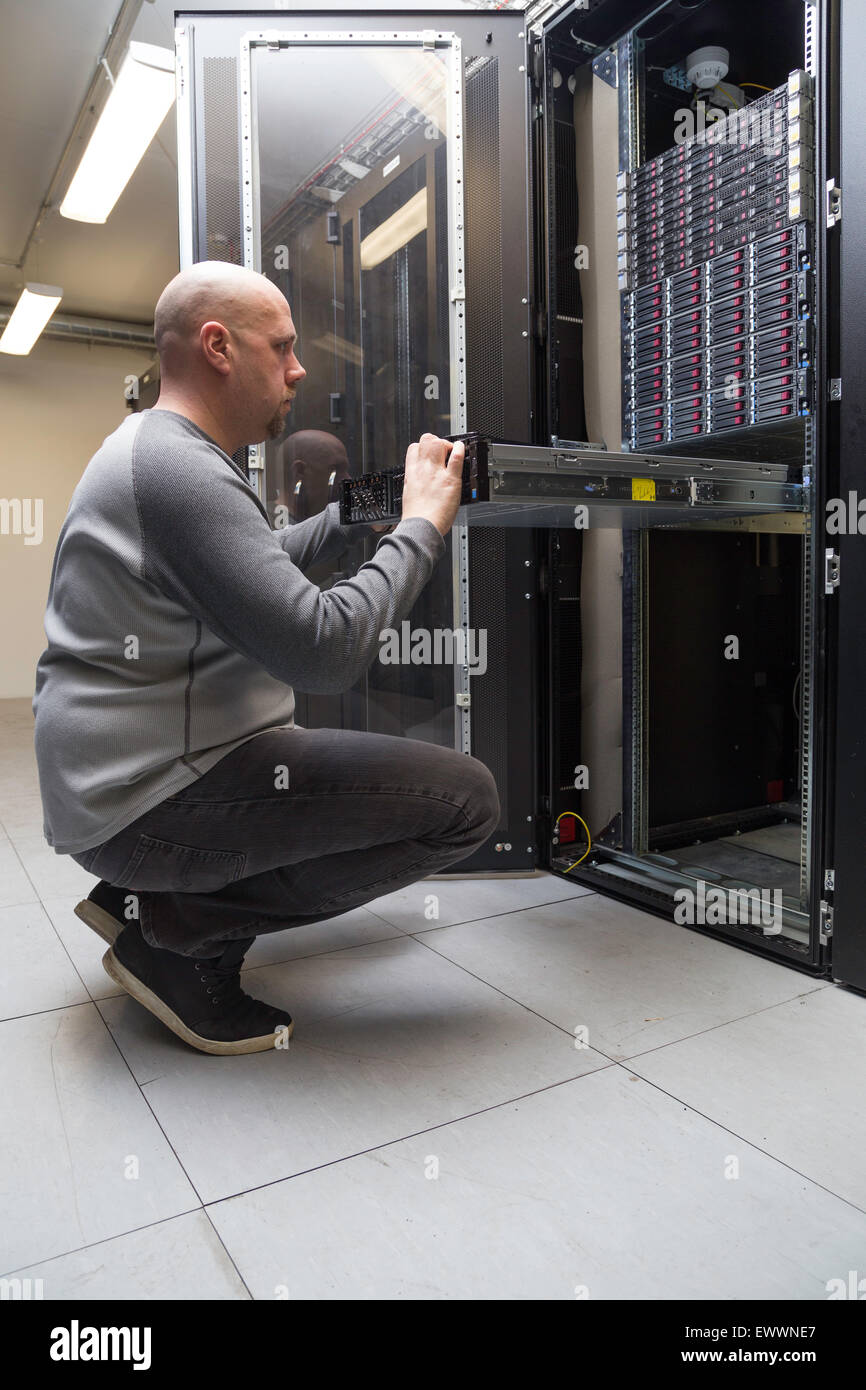 Administrador del sistema funciona en un servidor de red en una sala de servidores. Foto de stock
