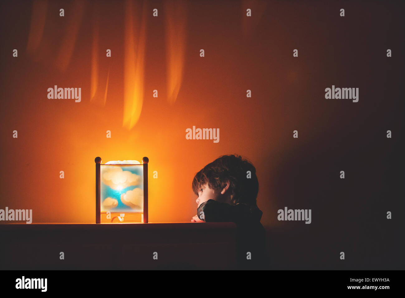 Un niño mirando una luz nocturna en su habitación Foto de stock