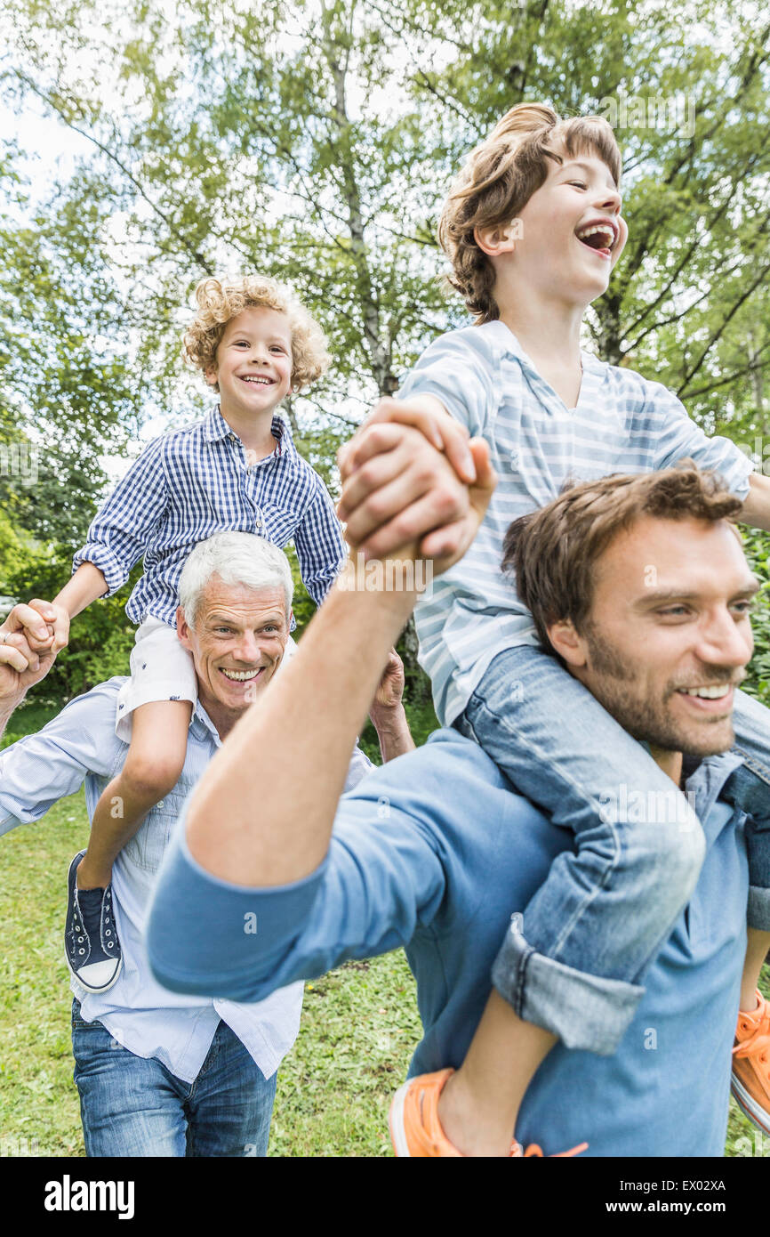 Mitad hombre adulto con el padre dando hijos hombro llevar en el jardín Foto de stock
