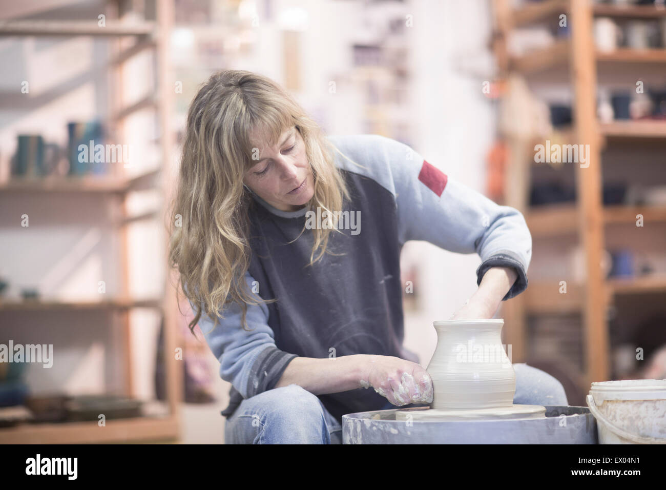 Potter femenino formando una vasija de barro en la cerámica en el taller de ruedas Foto de stock