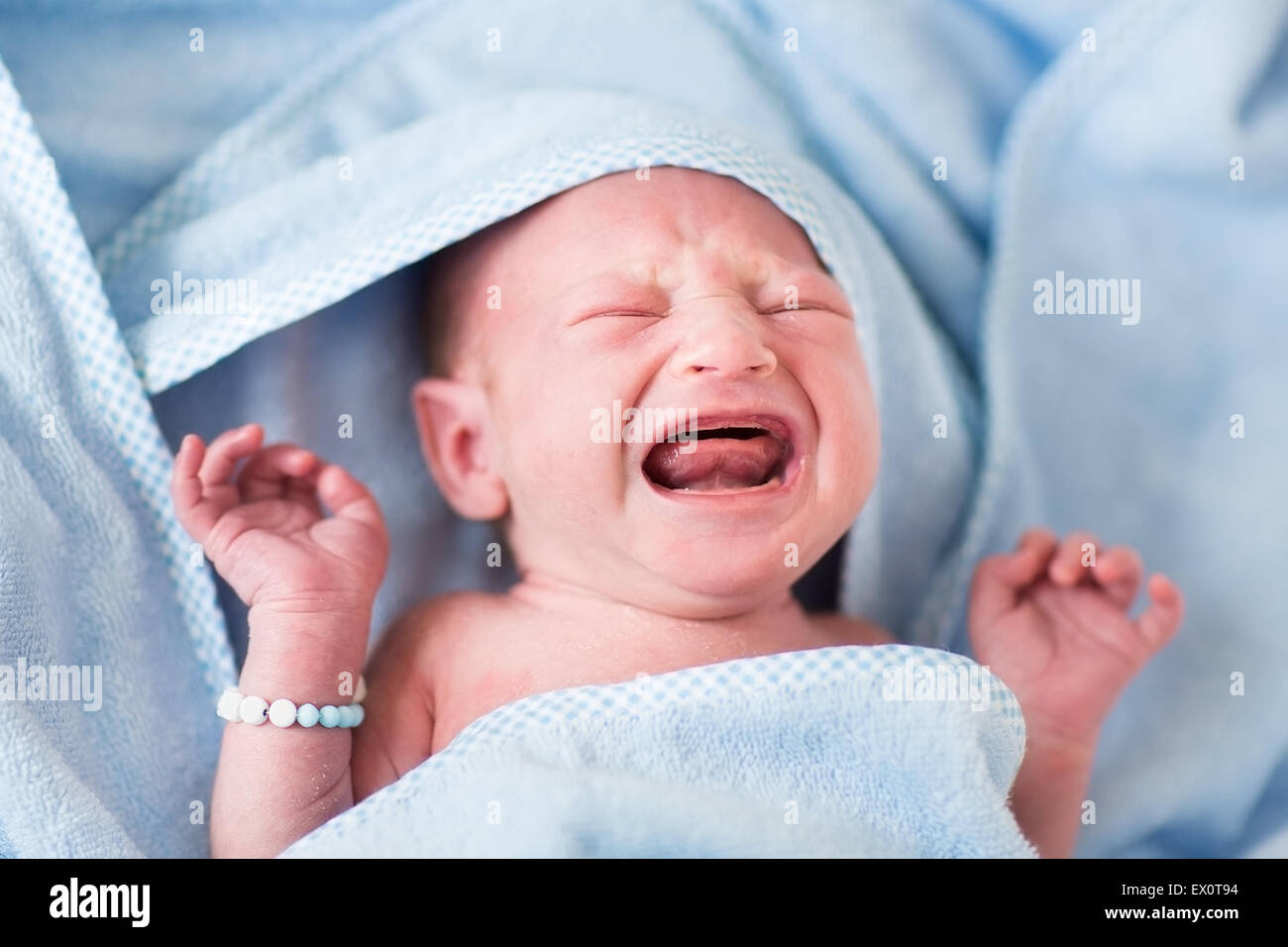 Tint bebé llorando después del baño en una toalla azul Foto de stock