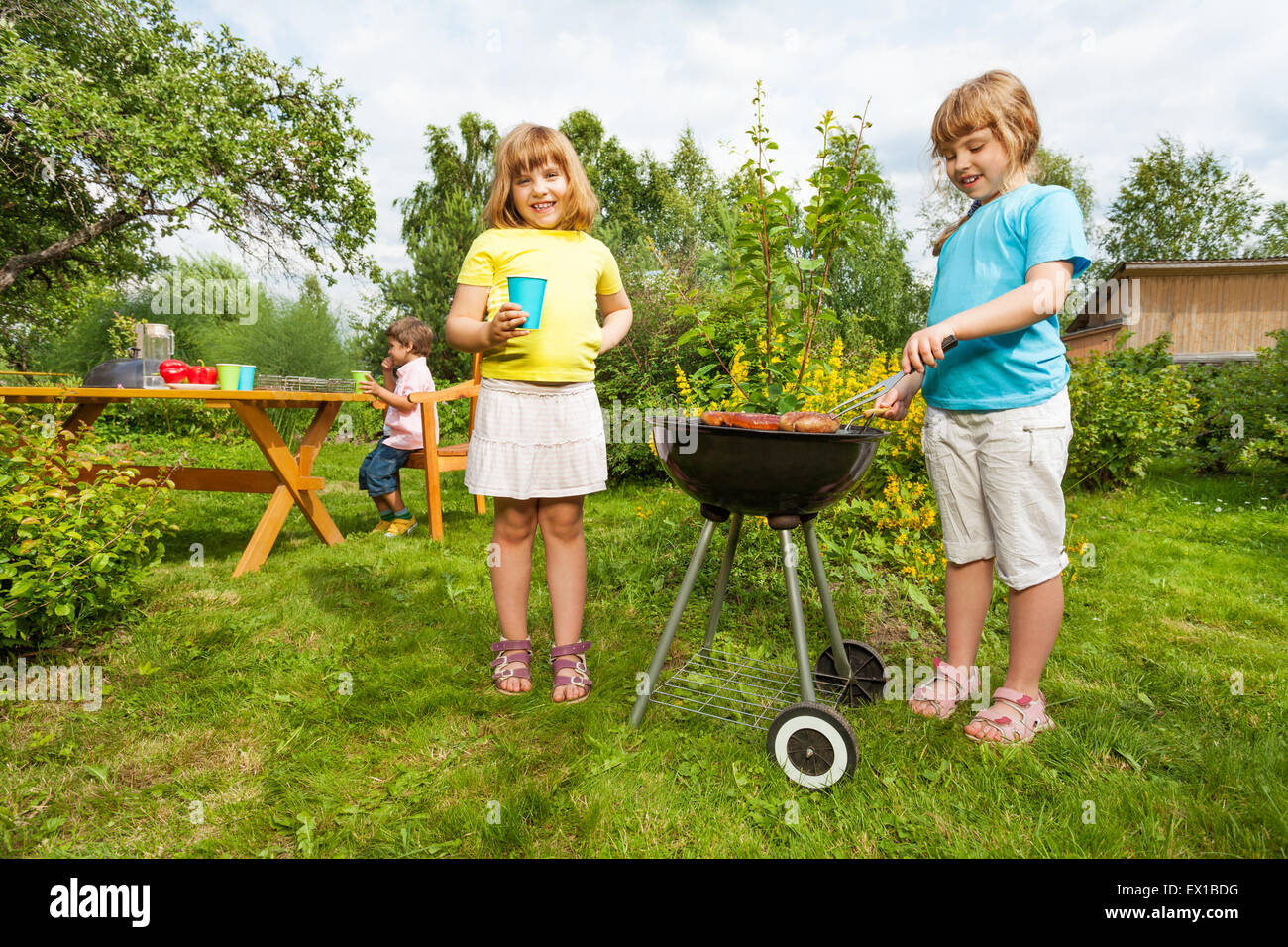 Dos niñas cerca de grill hacer barbacoa en el jardín Foto de stock