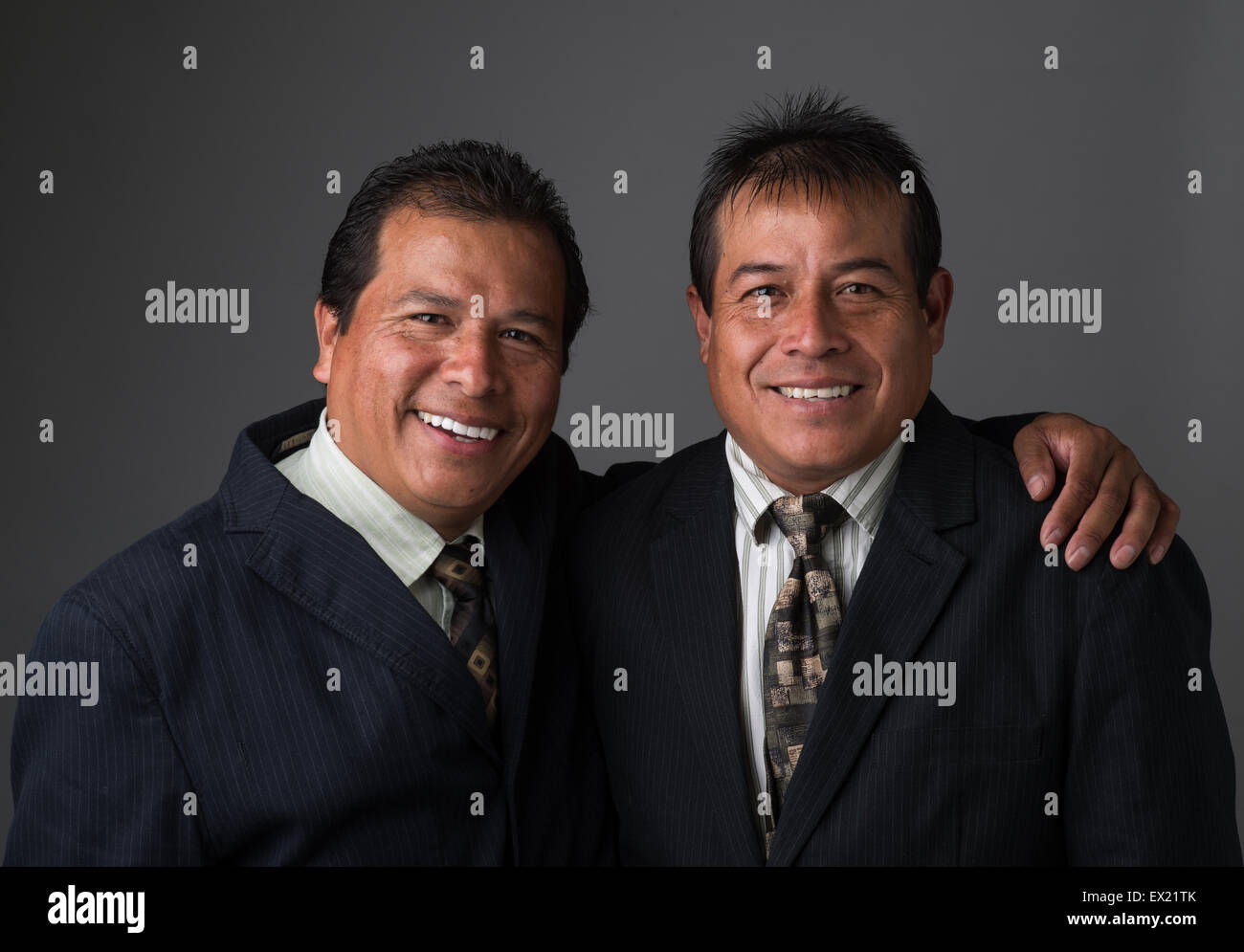 Hispanic Business hombres sonrientes en traje de negocios y corbatas posando para un retrato Foto de stock