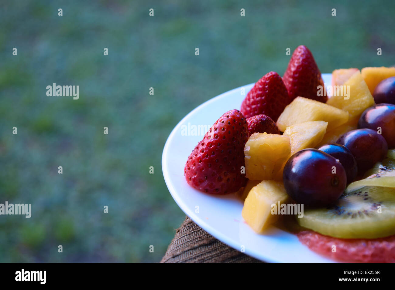 Rebanadas de fresas, uvas, piña, kiwi, naranja y pomelo en un plato. Plato de frutas. Foto de stock