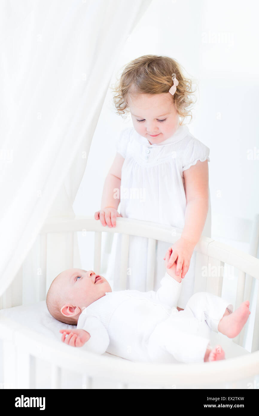 Hermanos, cute little toddler chica con pelo rizado vistiendo un vestido  blanco y su bebé recién nacido hermano, tomados de las manos Fotografía de  stock - Alamy