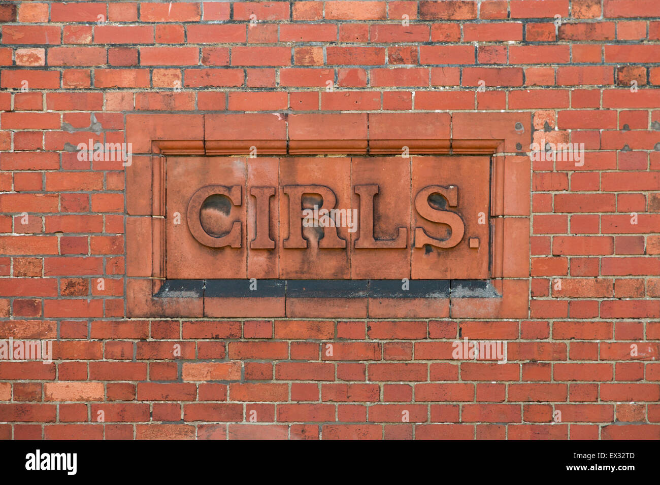 Las niñas firmar escritos en ladrillo en el lateral de un edificio escolar. Foto de stock