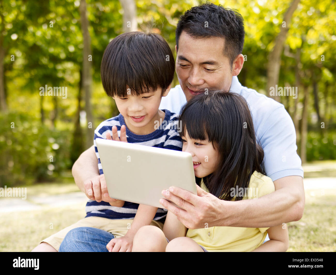 Padre e hijos mirando afuera de tablet pc Foto de stock