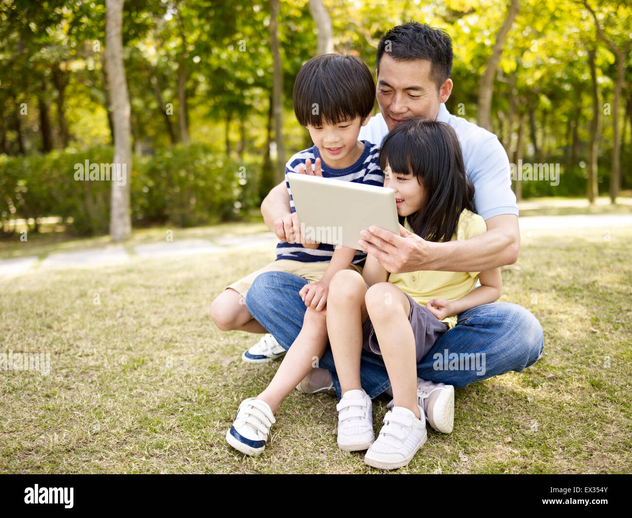 Padre e hijos asiáticos con tablet en estacionamiento Foto de stock