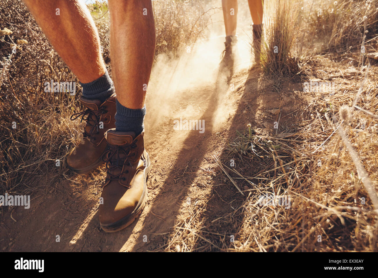 Bajo la sección foto de dos jóvenes caminando en el camino, se centran en los hombres las botas de trekking. Par de excursionistas en el país camine. Foto de stock