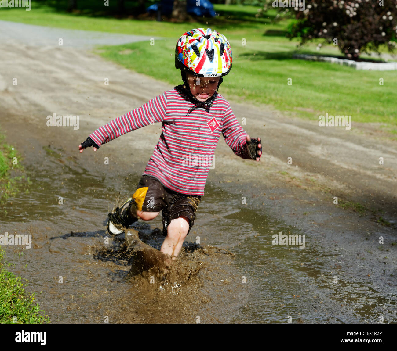 Un joven (3 años) muchacho saltando en un charco lodoso Foto de stock