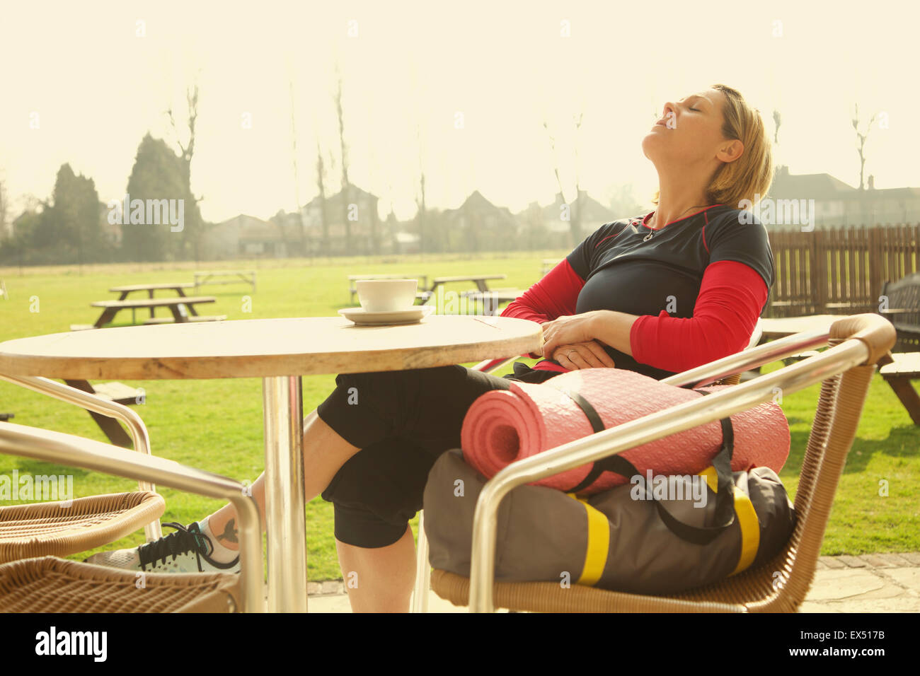 Mujer vistiendo ropa para hacer ejercicio relaja al café al aire libre Foto de stock