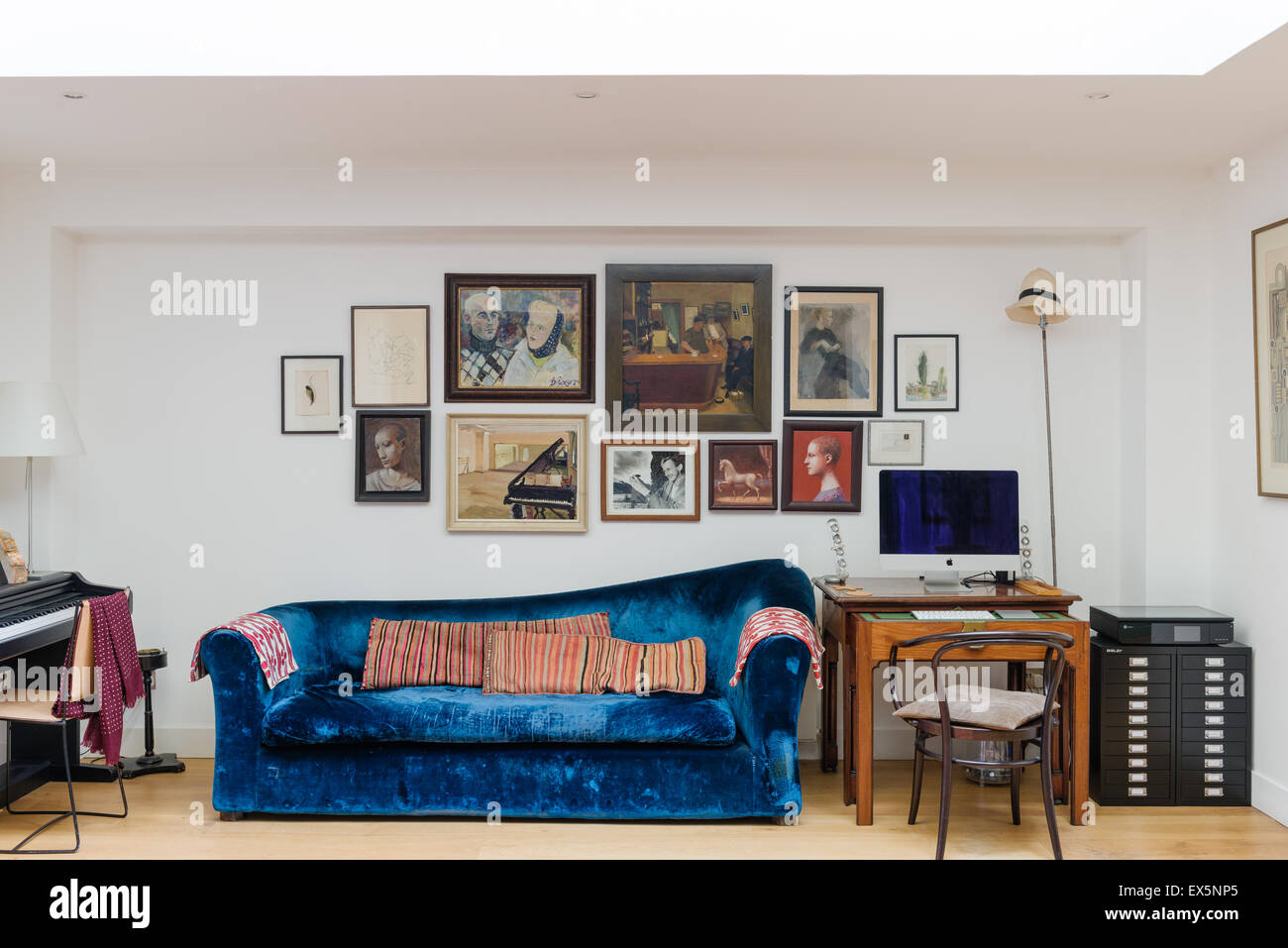 Blue Velvet Conran sofá en dawing habitación con variadas obras de arte Foto de stock