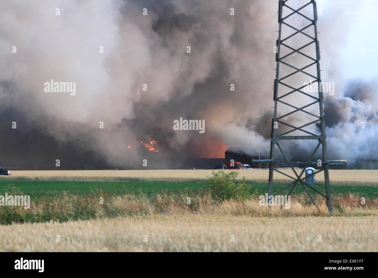 Rainham, Londres, Reino Unido. Martes, 7 de julio de 2015. Más de 80 bomberos abordar blaze en un astillero de palets en Rainham. 12 bomberos de tres bomberos fueron llamados a la escena alrededor de las 8:00pm el martes por la noche. Kent y Essex, bomberos y servicios de rescate fueron llamados para ayudar a afrontar la Brigada de Bomberos de Londres Blaze. Una pila de palets y un número de edificios están implicados en el incendio. Formulario de humo el incendio podría ser visto por millas alrededor de vientos atizado las llamas. No hay informes de lesiones y la causa de la llamarada no se conoce todavía. Foto de stock