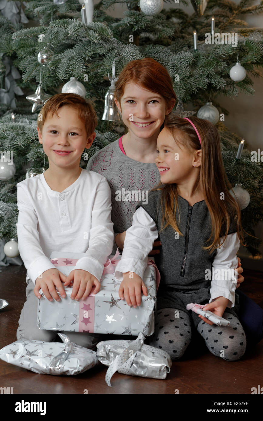 En la víspera de Navidad, Feliz Navidad hermanos con regalos bajo el árbol de Navidad, Baviera, Alemania Foto de stock