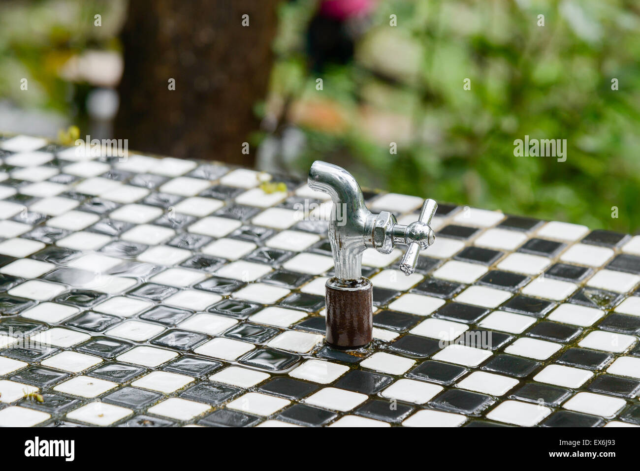 Grifo húmedo sobre una fuente de agua potable en el exterior en un día lluvioso. Foto de stock