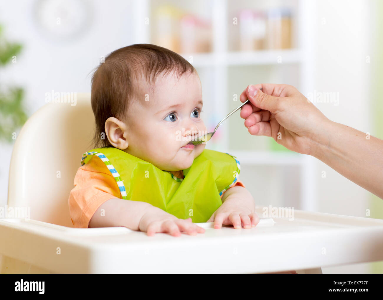 Funny Baby comiendo la comida en la cocina Foto de stock