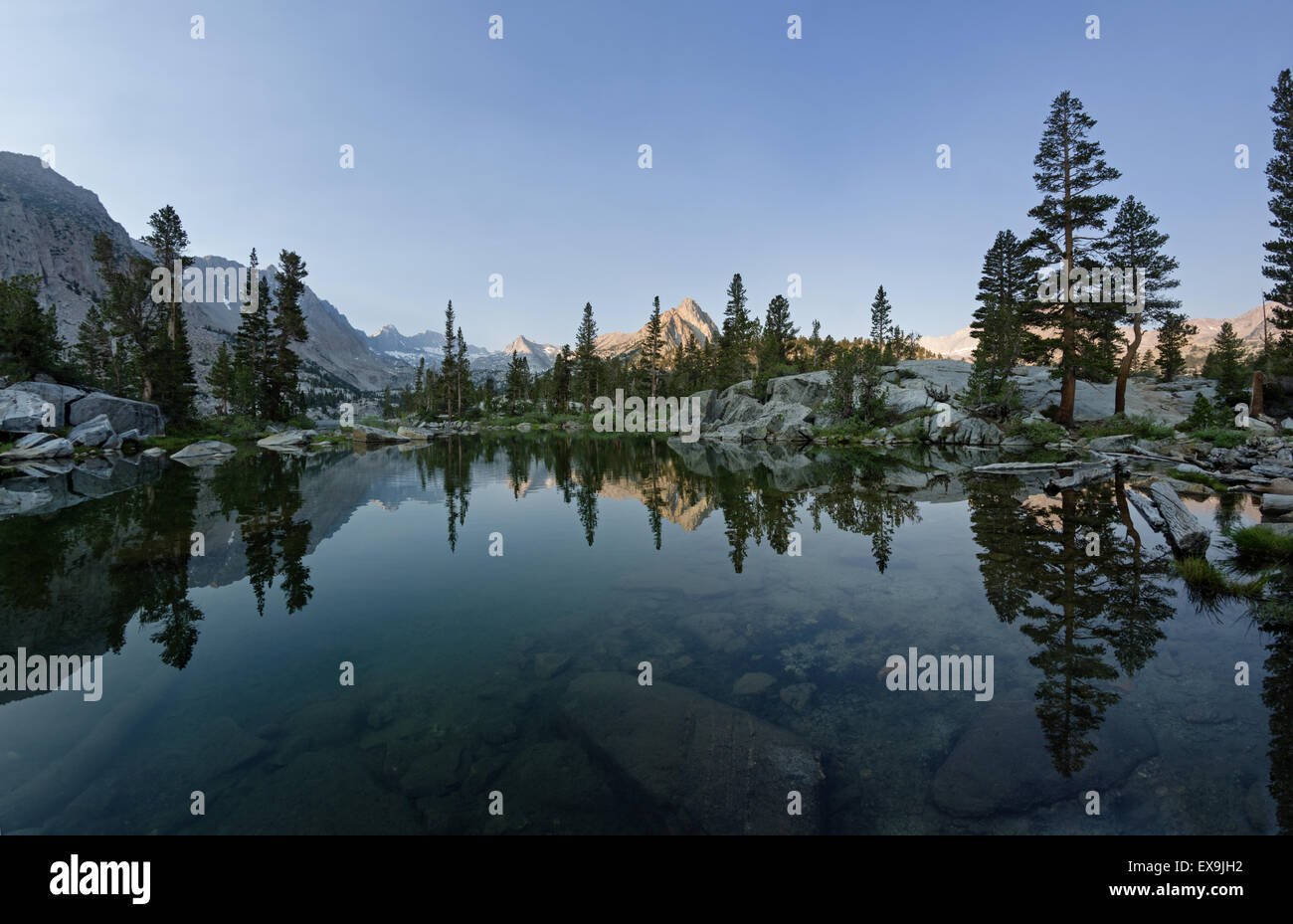 Reflejo de las montañas y árboles en lago azul en la mañana Foto de stock