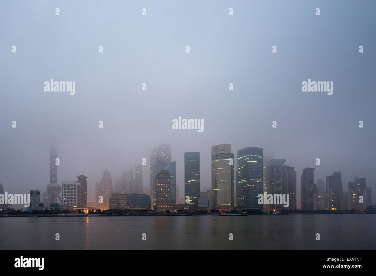 China, Shanghai, los rascacielos en el distrito de Pudong horizonte perdido en nubes bajas junto al río Huangpu en mañana de invierno Foto de stock