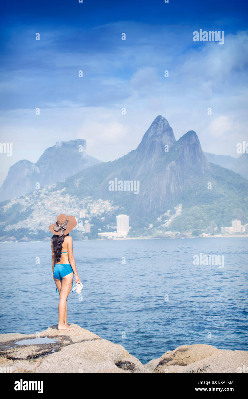 A 20-25 años mujer joven brasileña de pie en la roca de Arpoador, Rio de Janeiro, Brasil Foto de stock