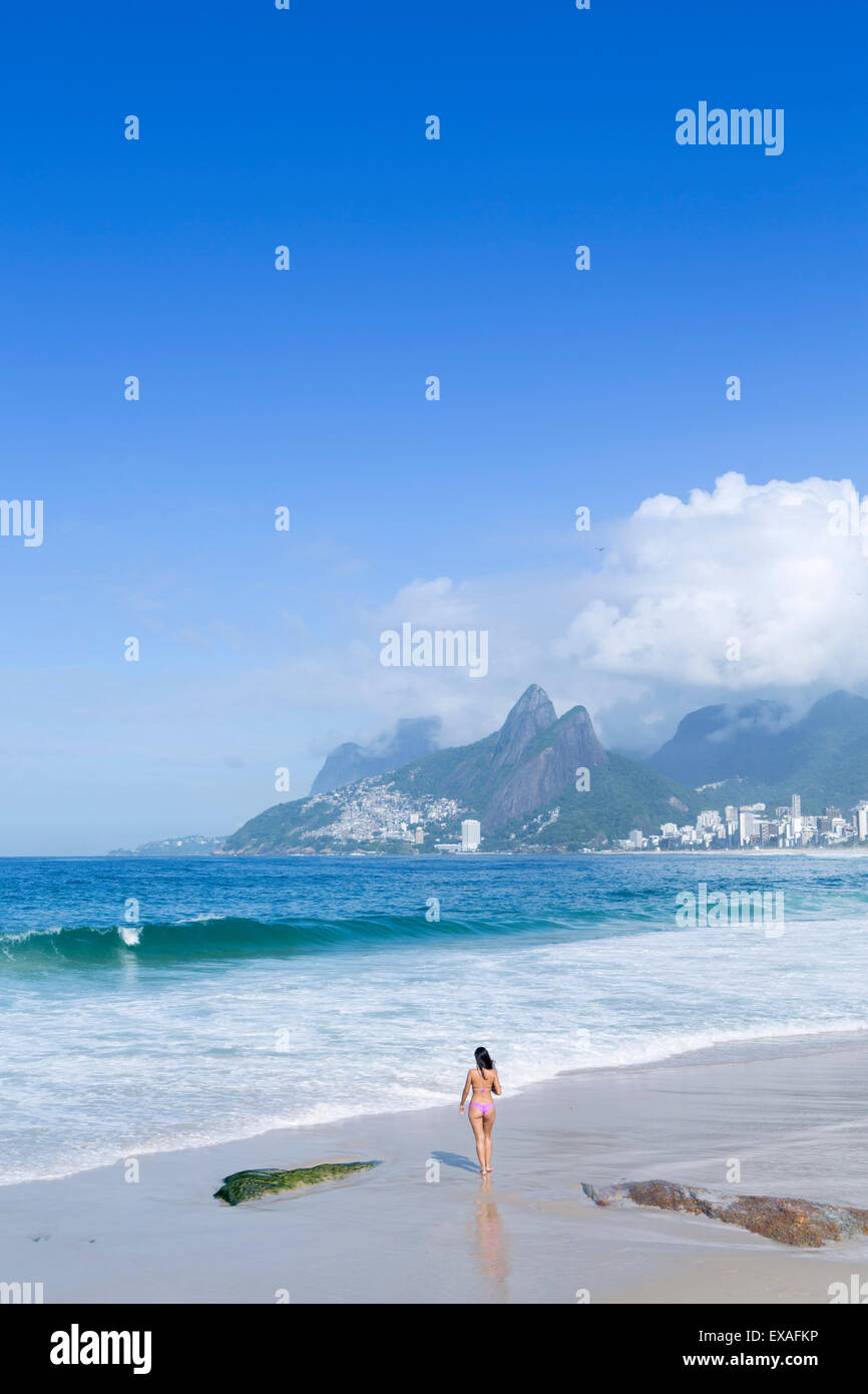 A 20-25 años mujer joven brasileña en la playa de Ipanema, con el Morro Dois Irmaos colinas en la distancia, Río de Janeiro, Brasil Foto de stock