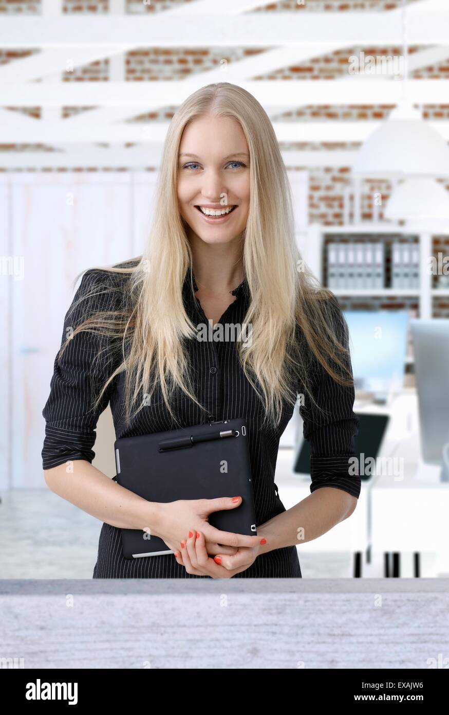 Retrato de feliz sonriente joven empresaria nórdicos sosteniendo una tableta, mirando a la cámara. Foto de stock