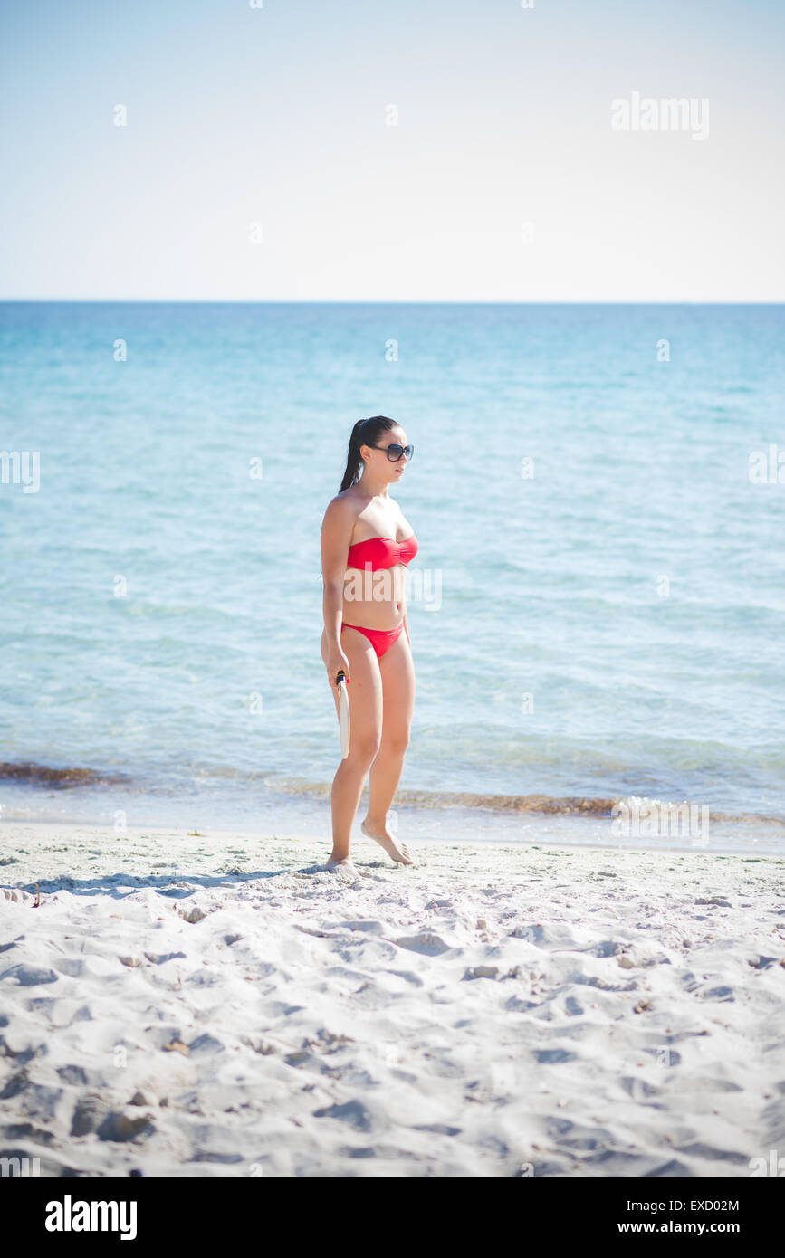 árabe giro Calumnia Morena hermosa joven mujer vistiendo el traje de baño y gafas de sol en  verano en la playa con raqueta Fotografía de stock - Alamy