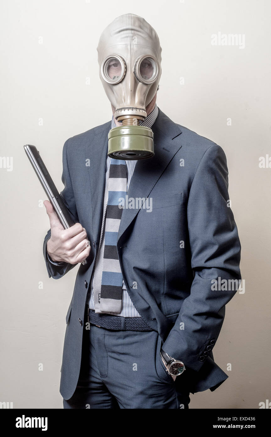 Empresario con máscara de gas con la notebook sobre fondo gris Foto de stock