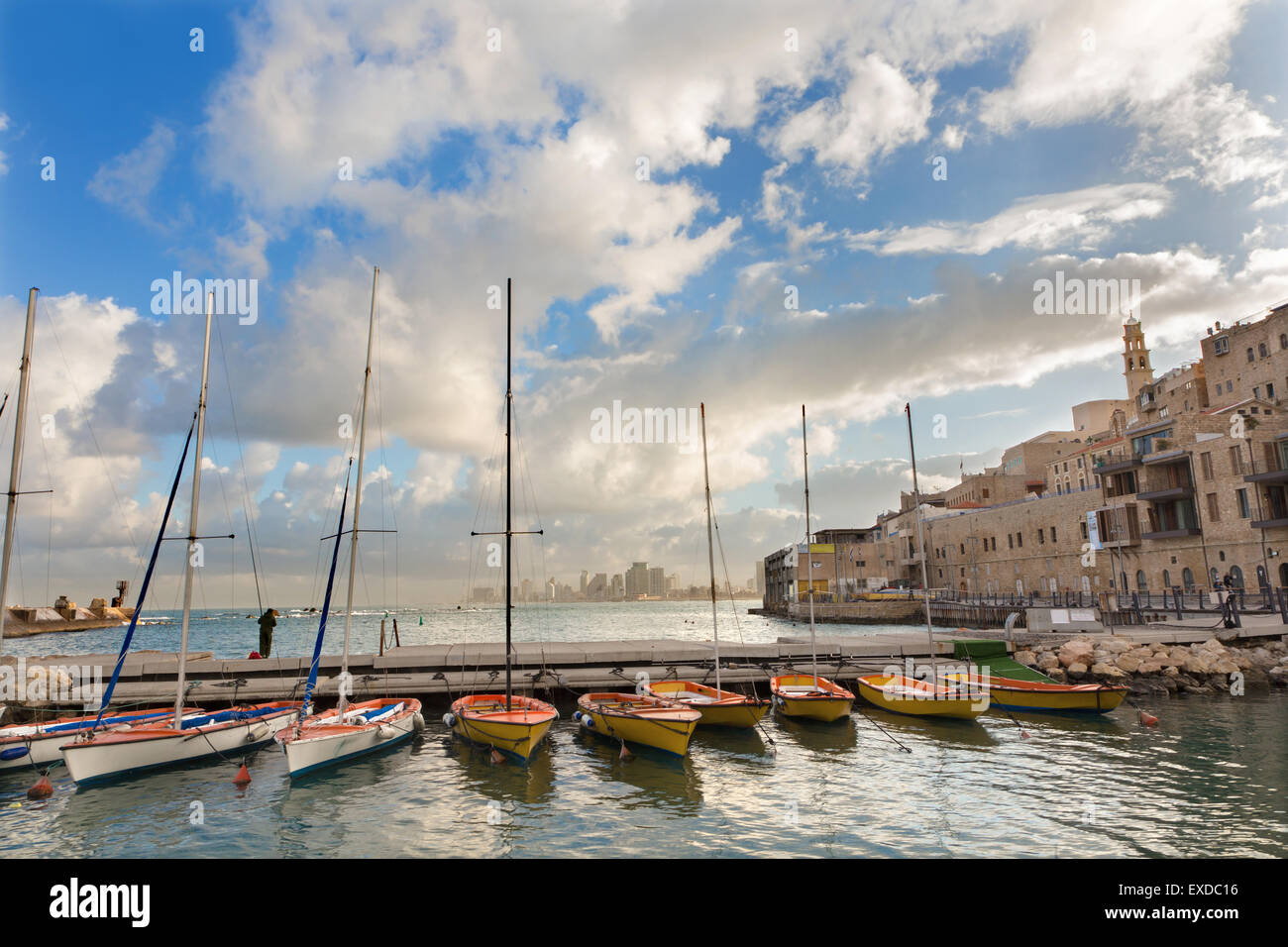 Tel Aviv - El pequeño puerto y yates bajo la vieja Jaffa y Tel Aviv en el fondo a la luz de la mañana y el hombre en la pesca. Foto de stock