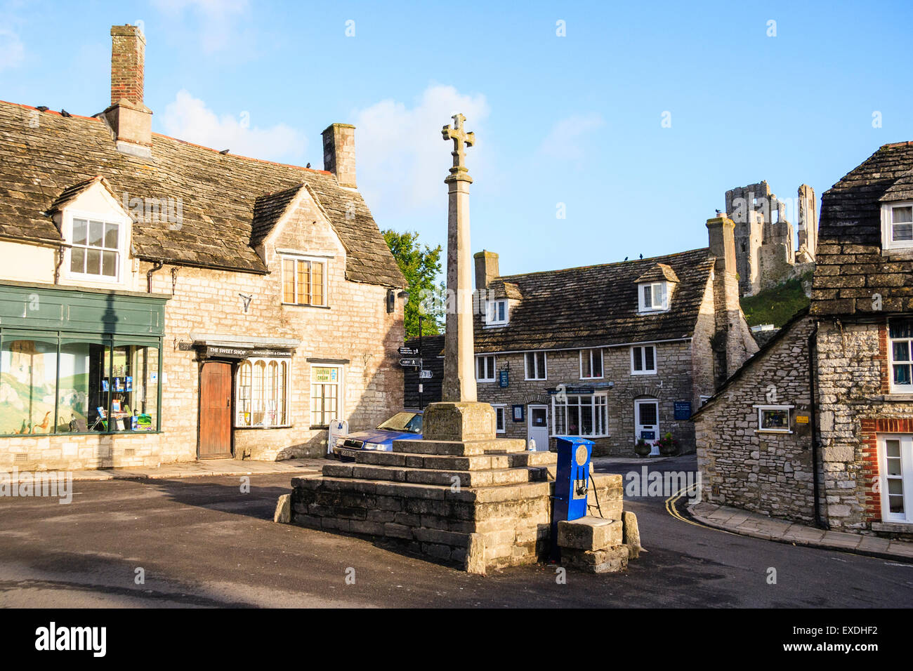 Típica plaza de pueblo inglés, Corfe, en Dorset. El primer plano es el pueblo de cruz, que también sirve como monumento conmemorativo de la guerra, y edificios de piedra caliza detrás. Foto de stock