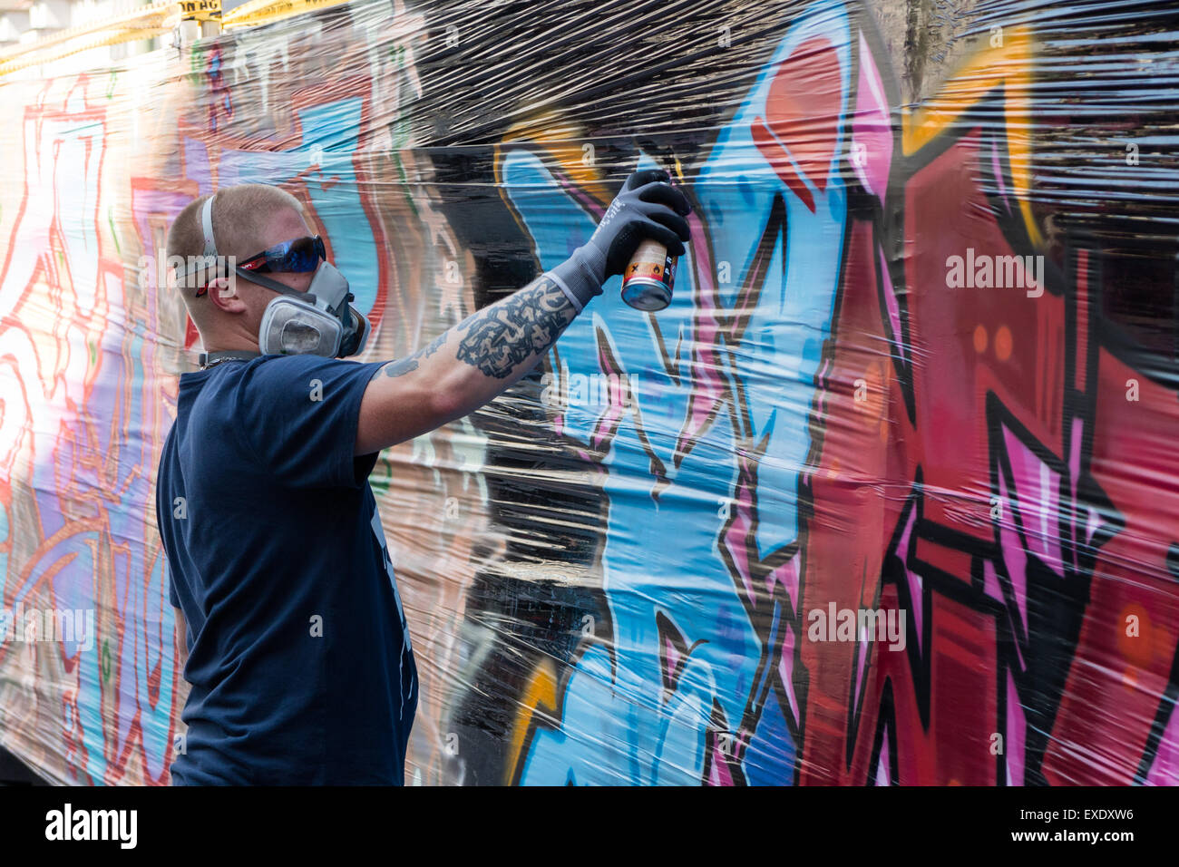 Un artista de graffiti utiliza una lata de pintura en aerosol en una pared  para pintar una imagen Fotografía de stock - Alamy