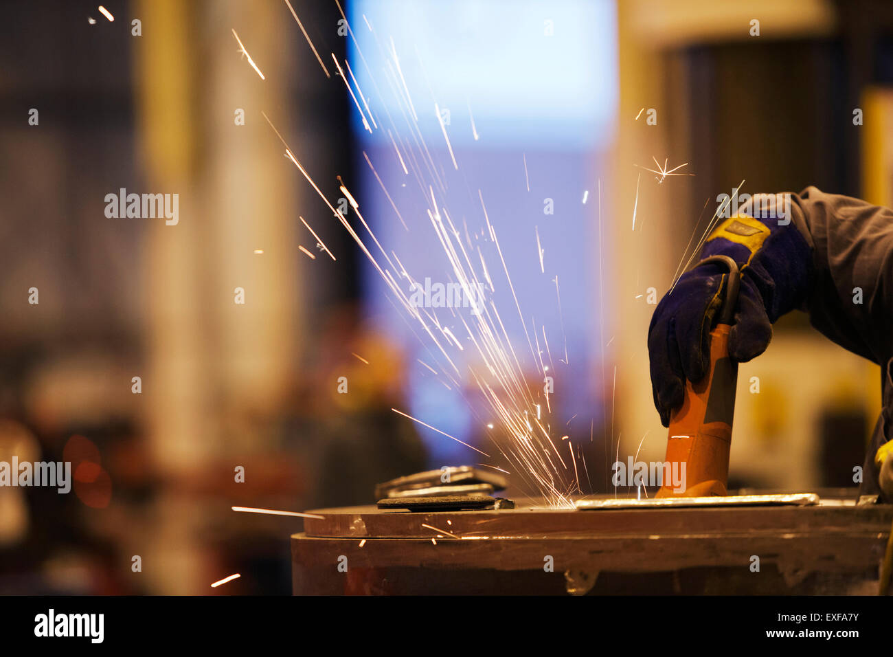 Las chispas de trabajador utilizando una muela abrasiva en la fábrica. Foto de stock