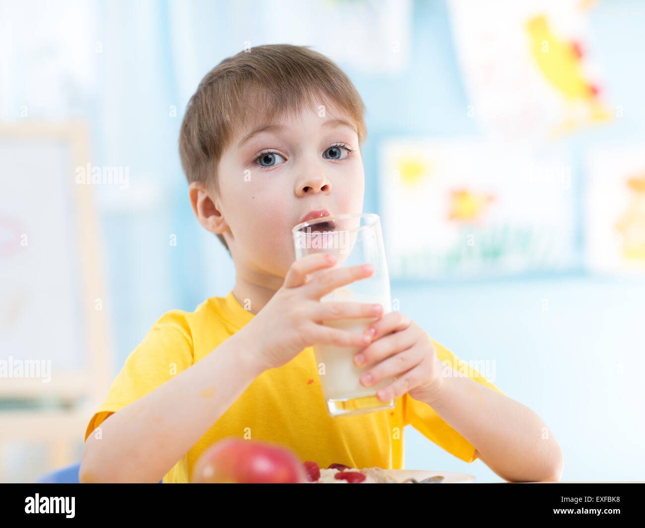 Niño bebe leche sana en casa o en el jardín de infantes Foto de stock