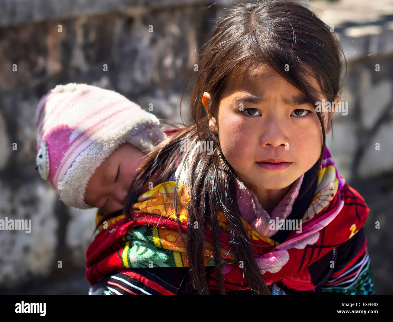 Bebé niña cargando Hmong no identificados y vistiendo el traje tradicional en la ciudad de Sapa, Lao Cai, Viet Nam. Foto de stock