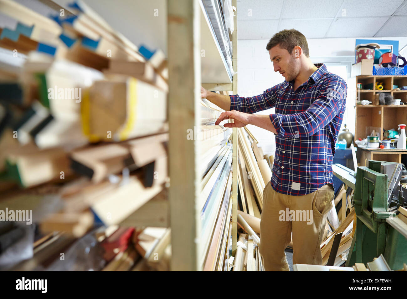 Mitad hombre adulto buscando stockroom estantes en marcos de imágenes taller Foto de stock