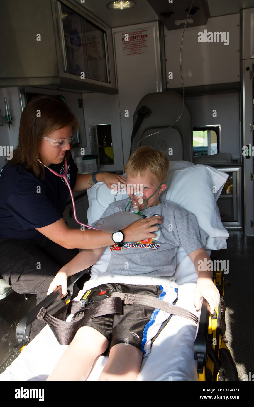 Paramédico femenino ayudando a paciente del sexo masculino y joven en la parte posterior de la ambulancia. Foto de stock