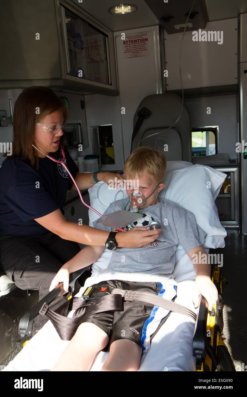 Paramédico femenino ayudando a paciente del sexo masculino y joven en la parte posterior de la ambulancia. Foto de stock