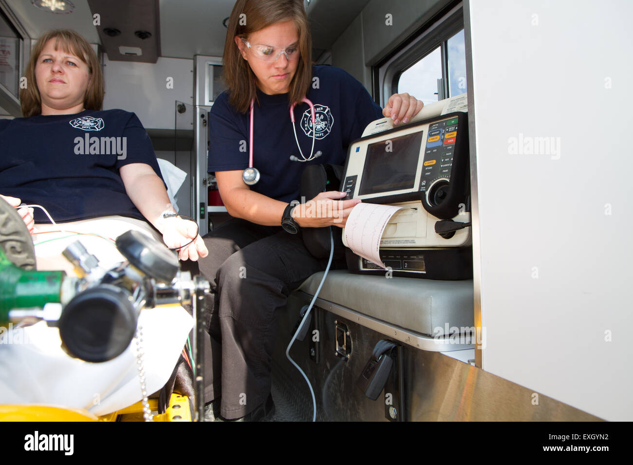 Mujeres paramédicos trabajando en la parte de atrás de una ambulancia. Bomberos voluntarios rurales nosotros. Foto de stock