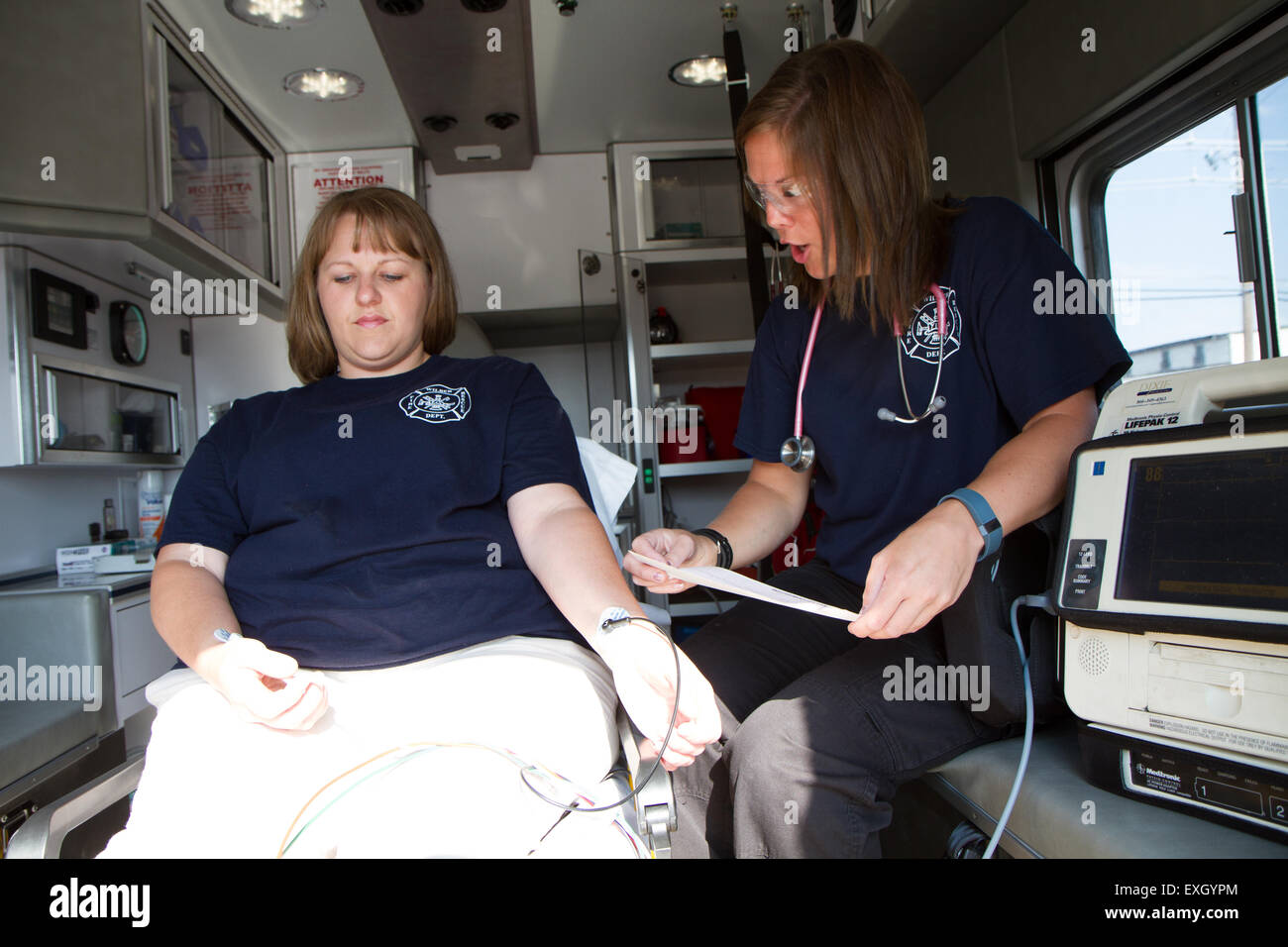 Mujeres paramédicos trabajando en la parte de atrás de una ambulancia. Bomberos voluntarios rurales nosotros. Foto de stock