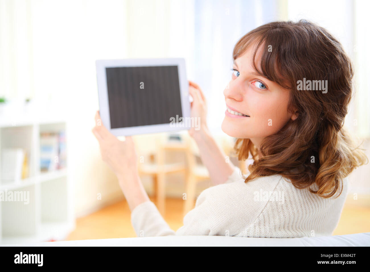 Vista de una joven mujer sonriente con un tablet en un sofá Foto de stock