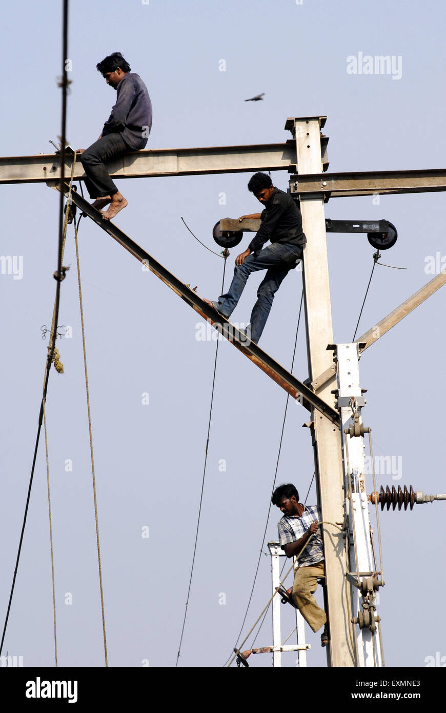 Trabajadores reparando cables aéreos de la línea ferroviaria, Bombay